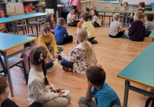 Dzieci słuchają nauczycielki opowiadającej o zwiastunach wiosny